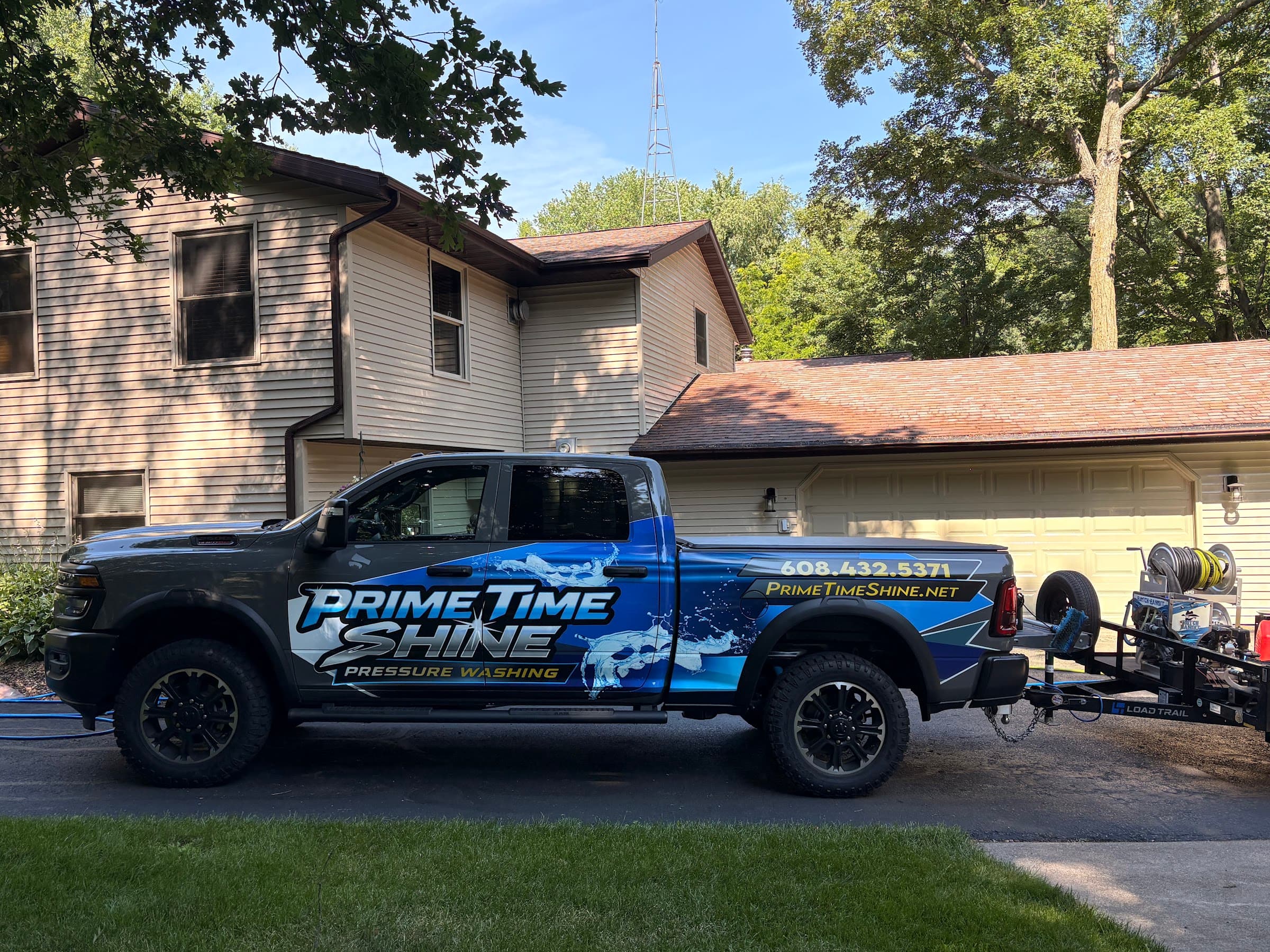 Prime Time Shine's blue and black work truck and cleaning trailer outside a home